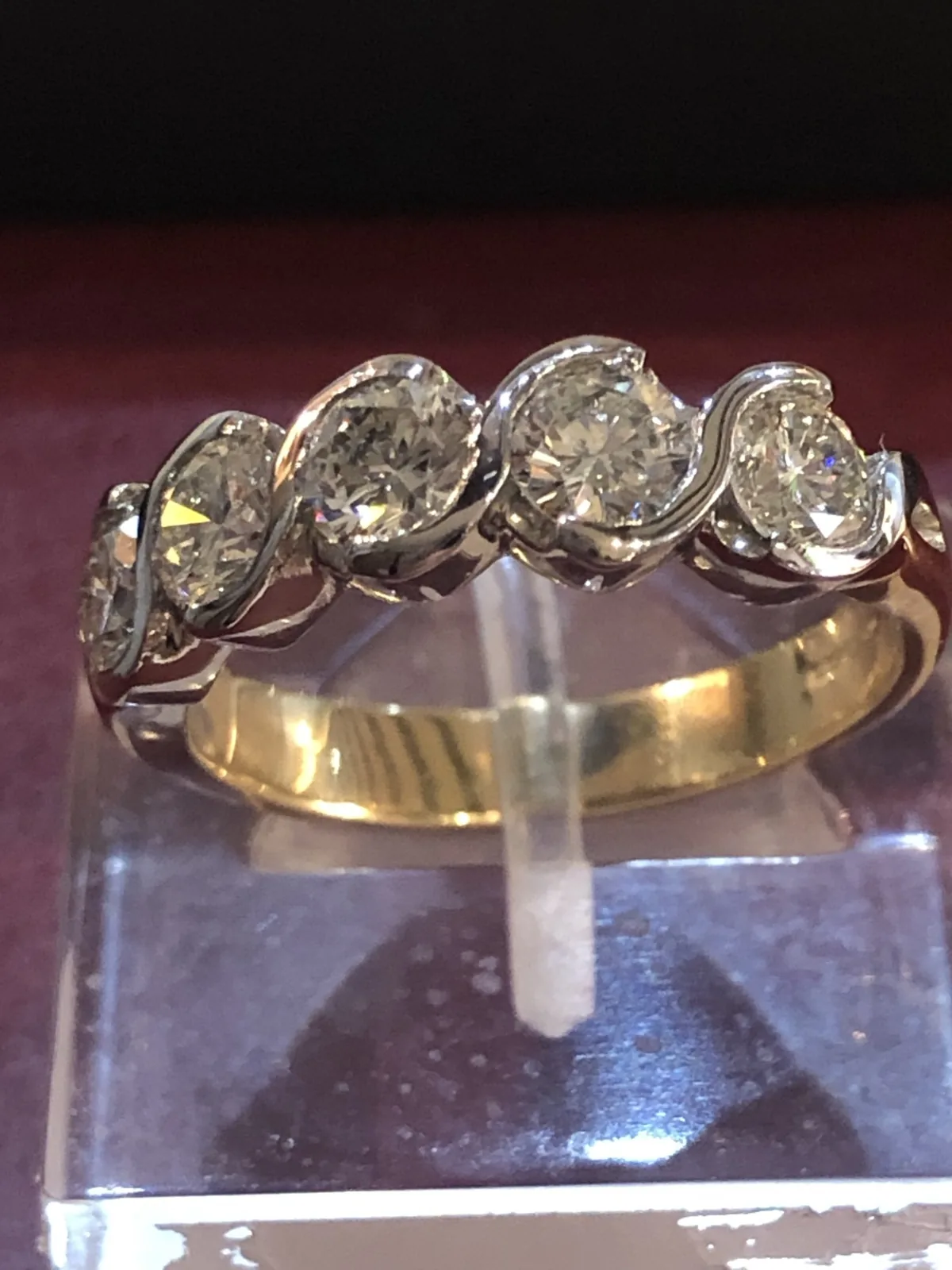 Five round diamonds in a swirling white and yellow gold band