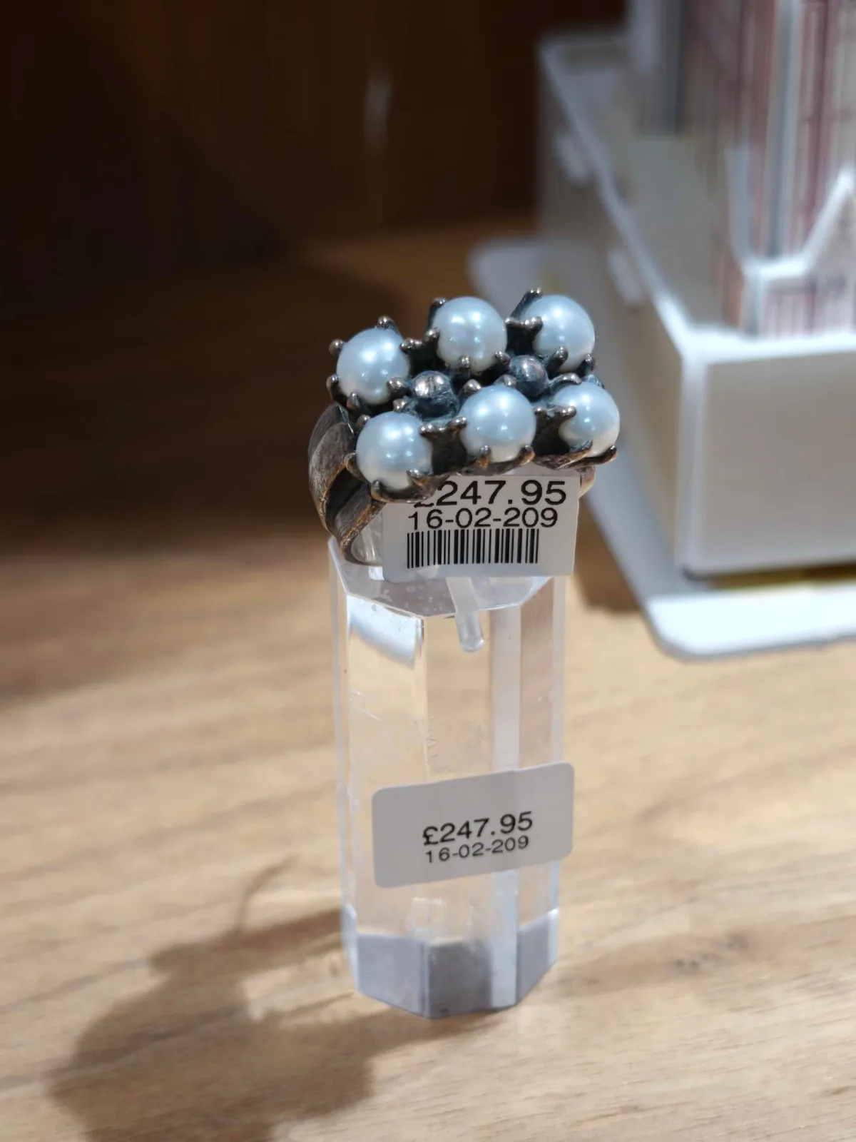 A cluster ring set with pearls on a display stand