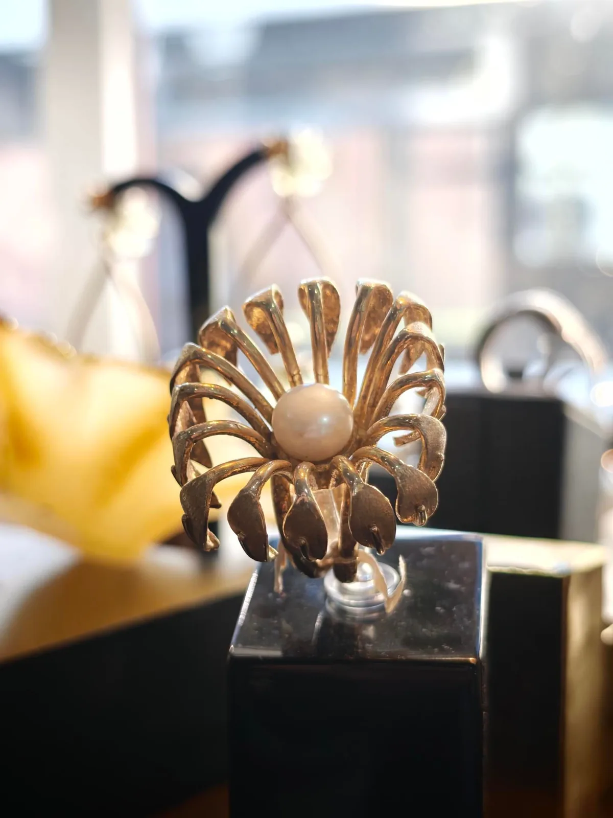 A gold flower brooch with radiating petals and a pale centre