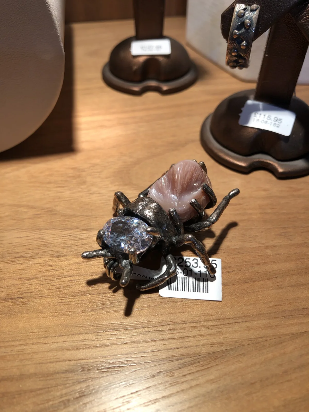 A silver bee brooch on a wooden counter