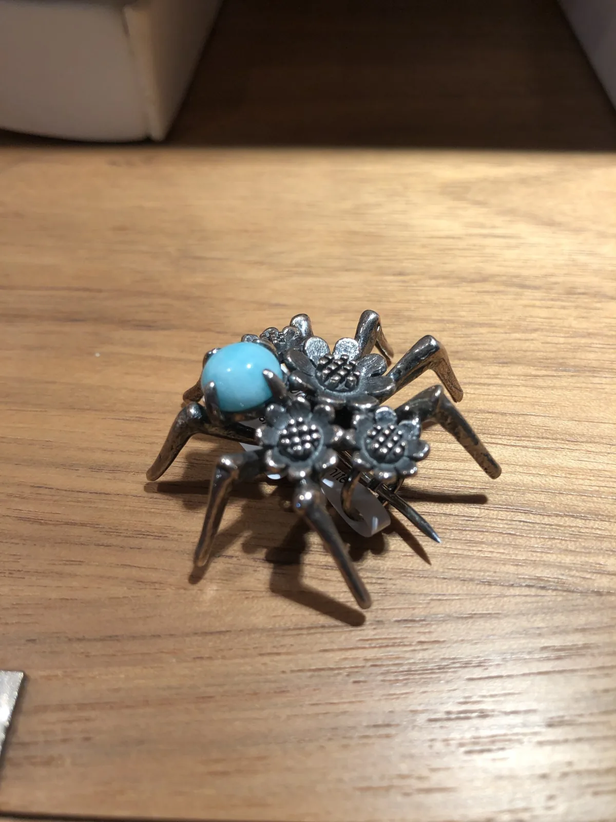 A silver spider brooch with a turquoise body